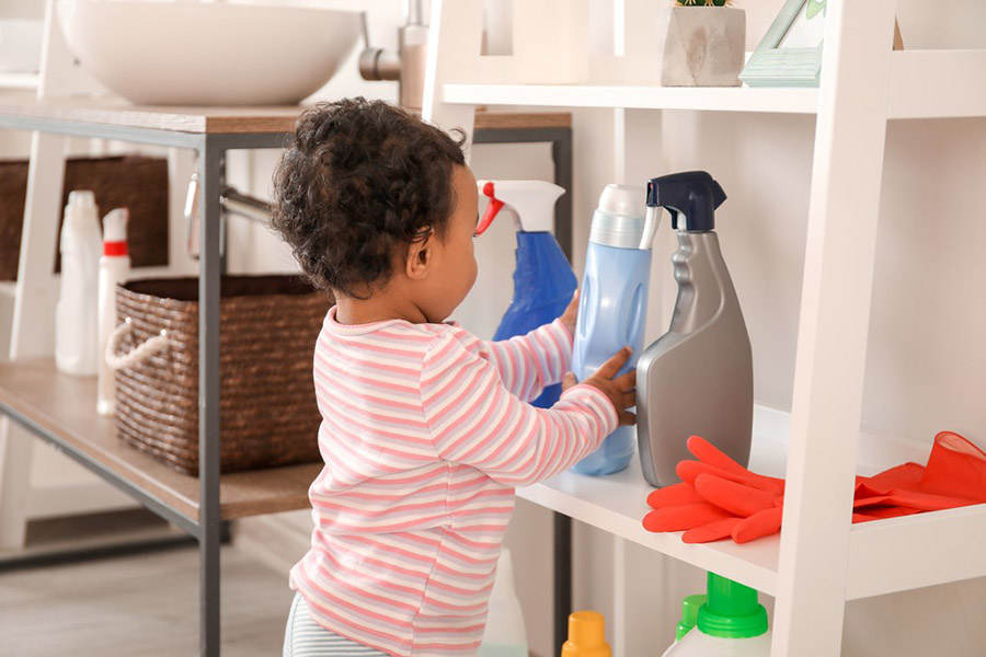 Child handling household cleaner on low shelf